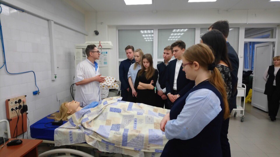 Преподаватель и школьники в симуляционном центре рассматривают манекен Преподаватель и школьники в симуляционном центре рассматривают манекен